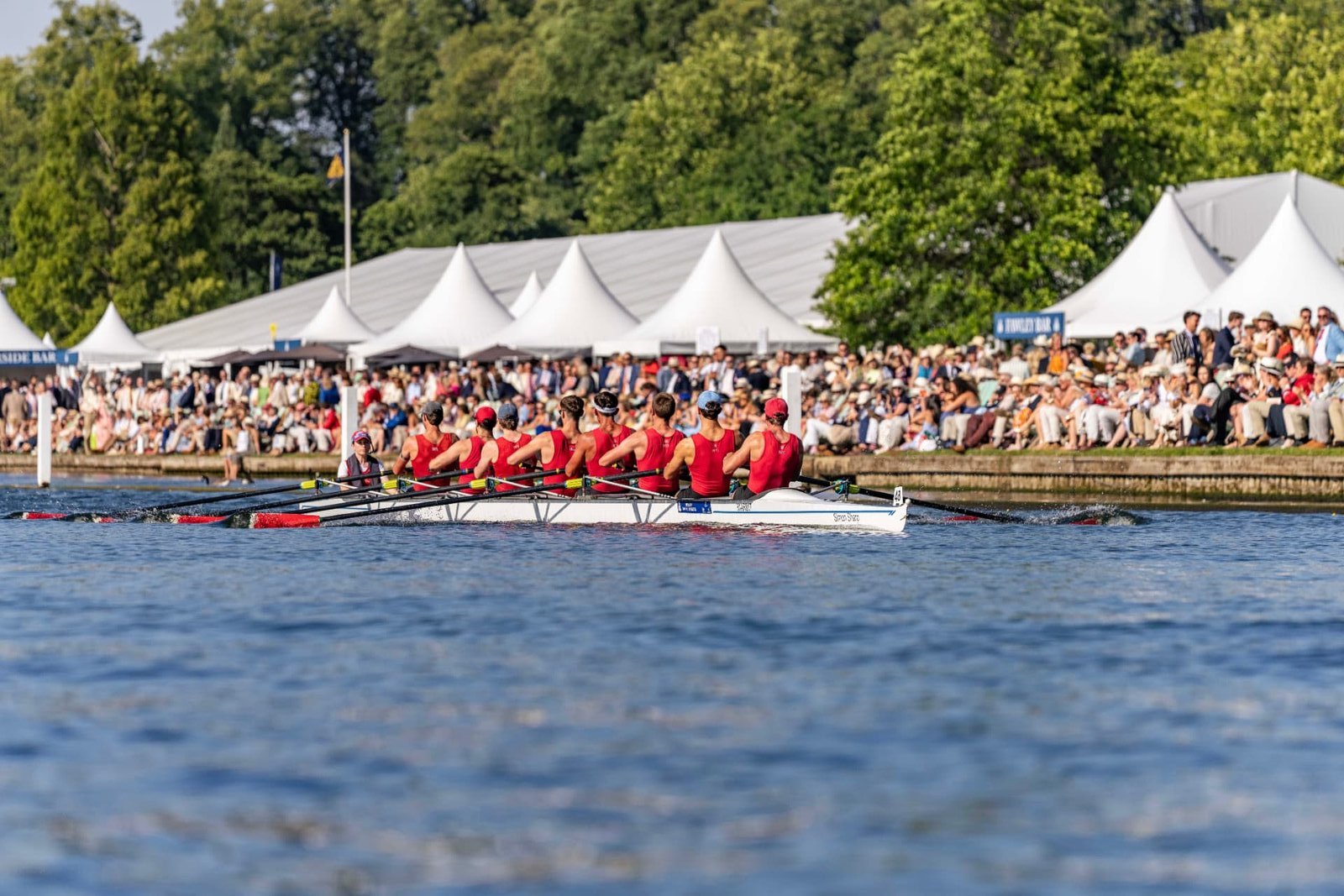 A women’s eight racing past the crowded enclosures at Henley Royal Regatta